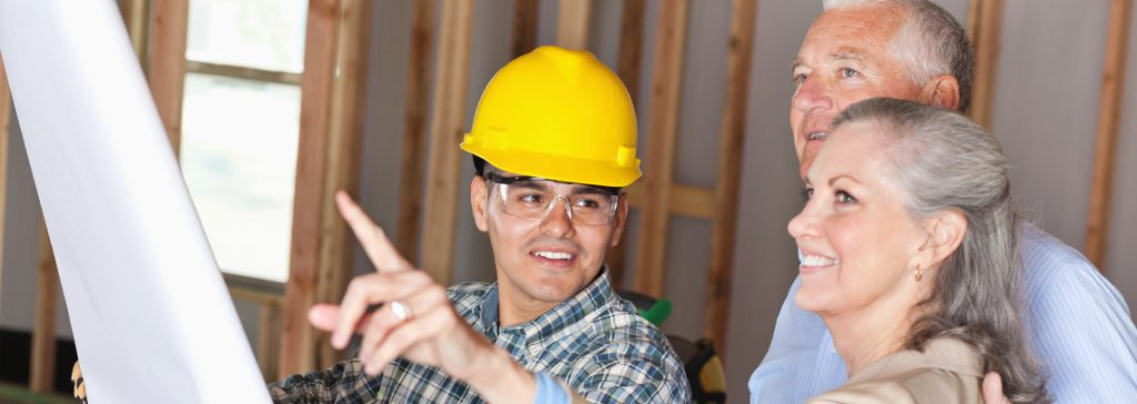 Group of construction workers looking at blueprints and talking outdoors