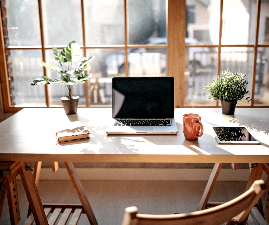 desk with a laptop and two chairs and plants